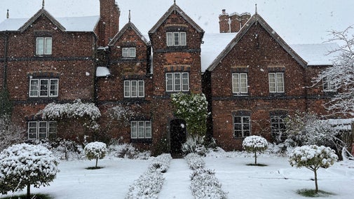 The front exterior of Moseley Old Hall with snow on the ground and roof of the building. Snow is also seen falling in the image.